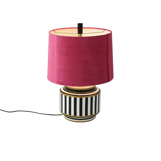 Tischlampe mit gestreifter Keramikbasis und leuchtend rosa Lampenschirm.